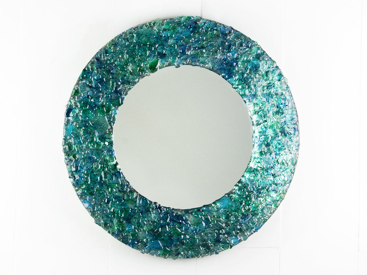 Fused glass round mirror handmade using crushed, recycled glass to create an ocean inspired piece of wall art. 