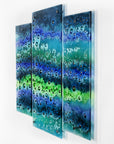 A fused glass staggered triptych featuring an ocean inspired design, with a blend of coastal blues and sea greens, handmade with organic bubbled texture and reflections.