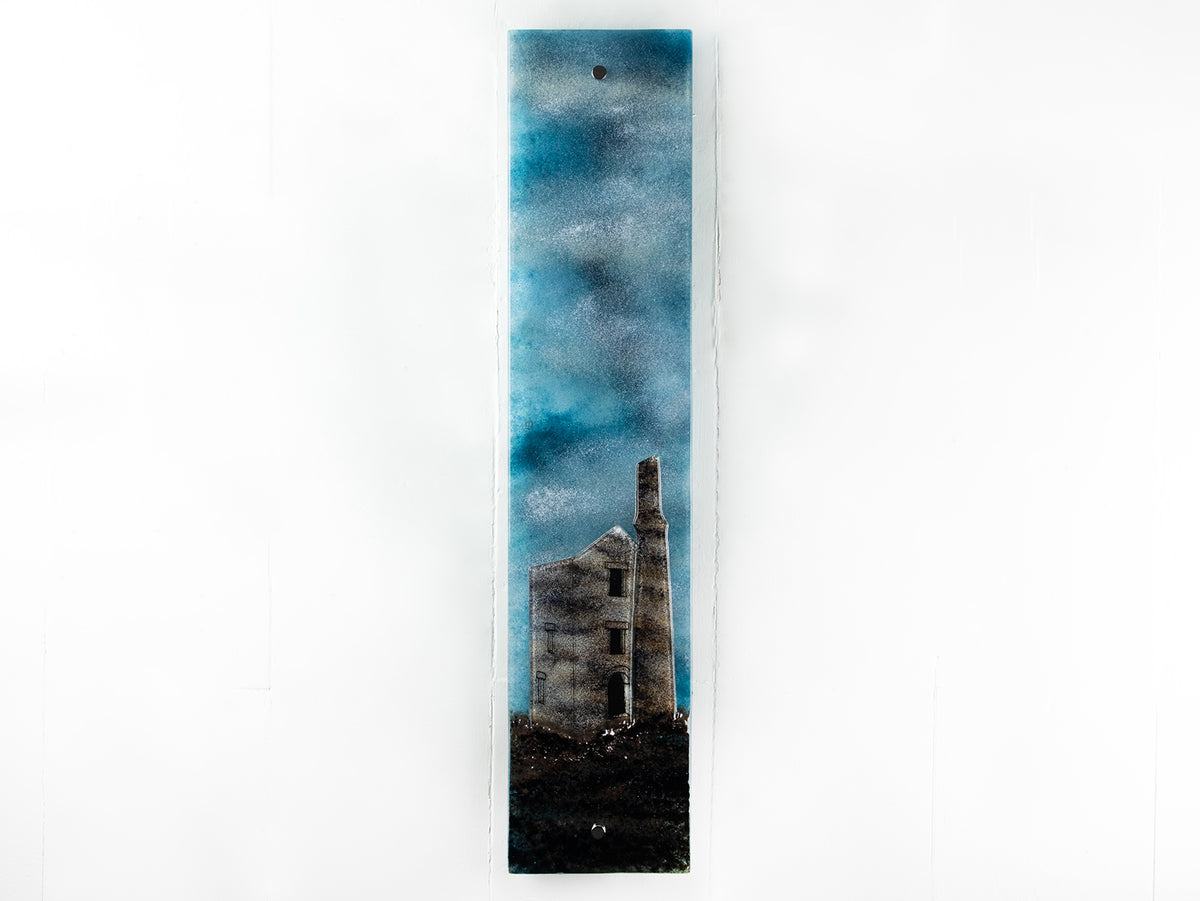 Fused glass tin mine wall panel set against a moody dark sky, creating a soft Cornish inspired piece of wall art. 