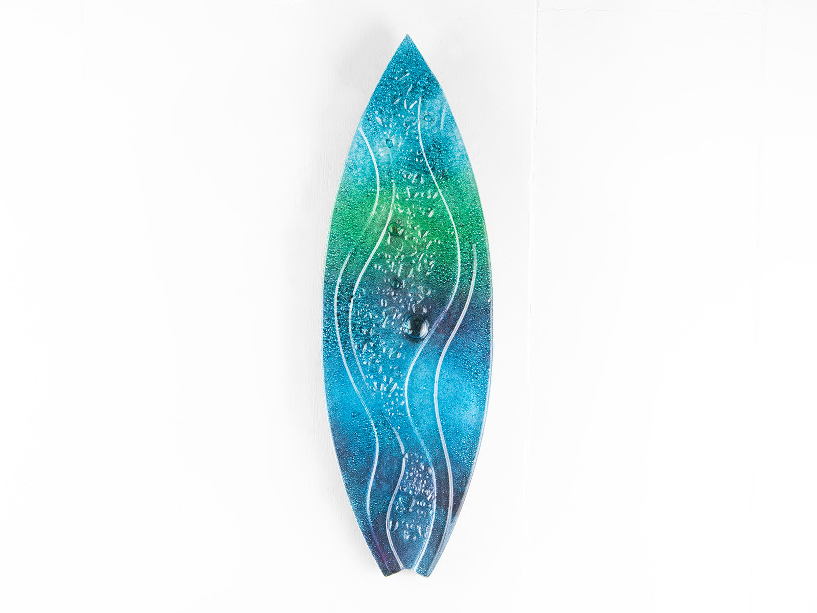 A surfboard-shaped wall art piece featuring a sea blue and green colour-way with soft waves and textured detailing. 