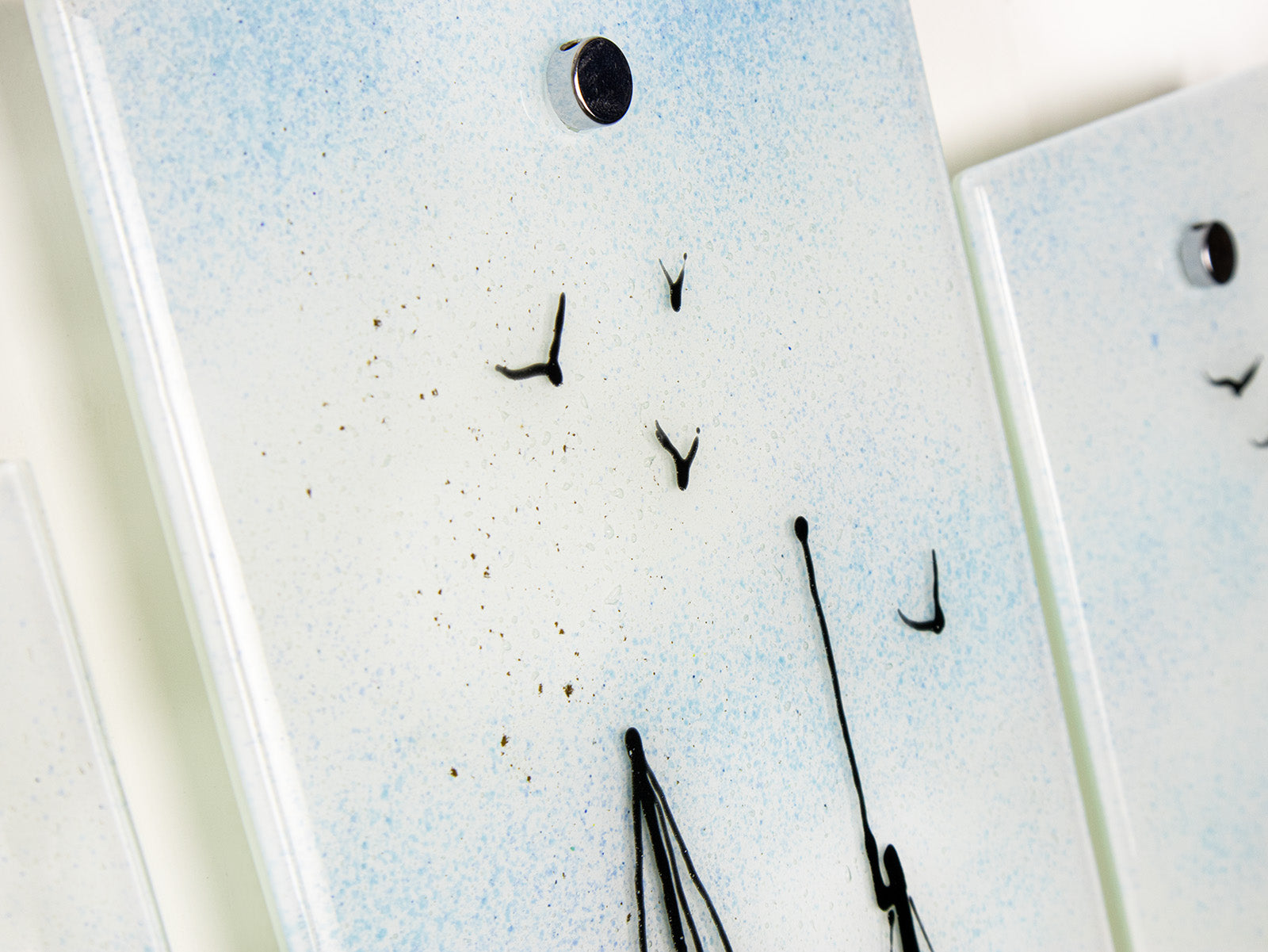 A close up of distant soaring birds on a staggered fused glass wall art triptych, with hand-painted fishing boat and a soft costal colour-way. 