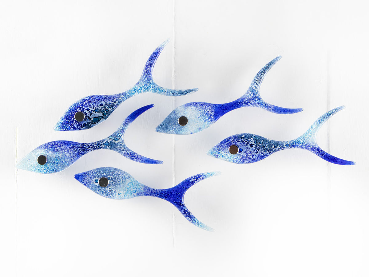 Five fused glass fish in a shoal shape in coastal blues. Handmade ocean inspired wall art.
