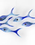 Five fused glass fish in a shoal shape in coastal blues. Handmade ocean inspired wall art.