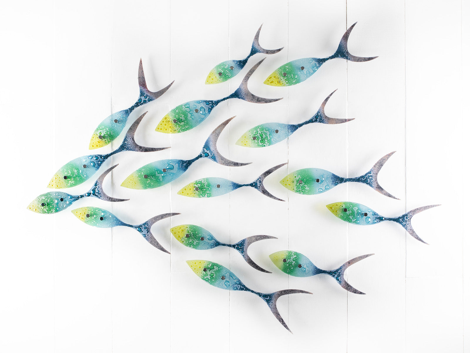 Fused glass ocean shoal of fish, in bright coastal yellows, purples, greens and blues. A vibrant ocean inspired wall art display. 