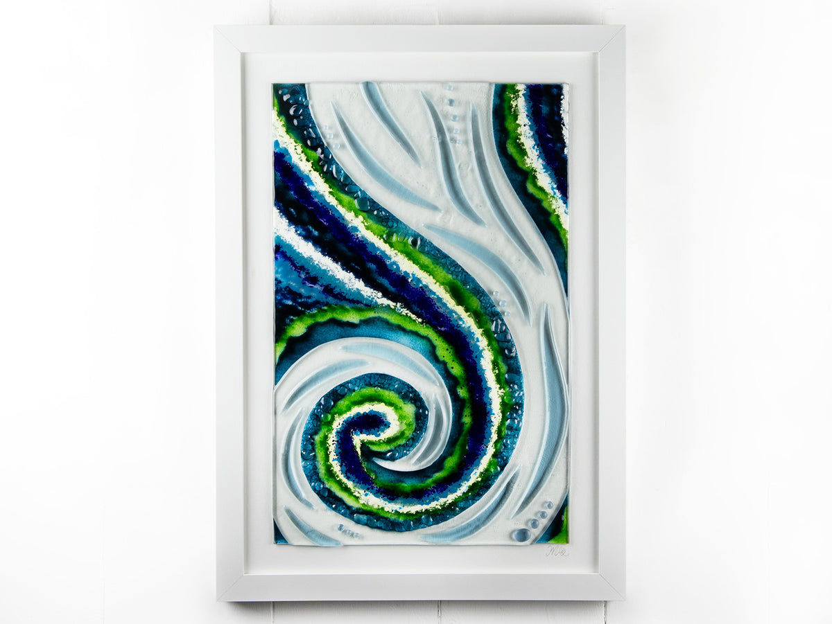 A fused glass large oblong art frame featuring an abstract tidal design in ocean blue and greens with textural detailing. A handmade coastal inspired piece of wall art. 