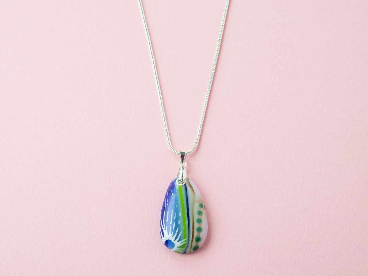 A Signature by Jo Downs fused glass pendant necklace, handmade using some of Jo's innovative techniques in soft botanical and ocean colours. Finished with a sterling silver chain and fittings.