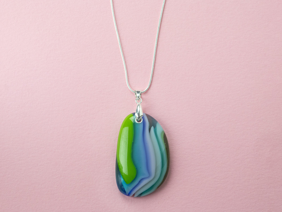 A sterling silver chain necklace with a fused glass pendant featuring a marbled swirl pattern of green, blue, and blushed white. 
