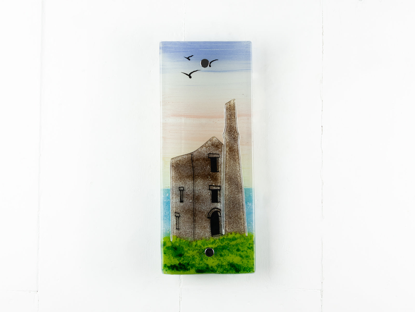 A fused glass extra small wall panel, featuring soft sunset sky, coastal landscape, soaring birds and a Cornish tin mine. A handmade piece of wall art. 