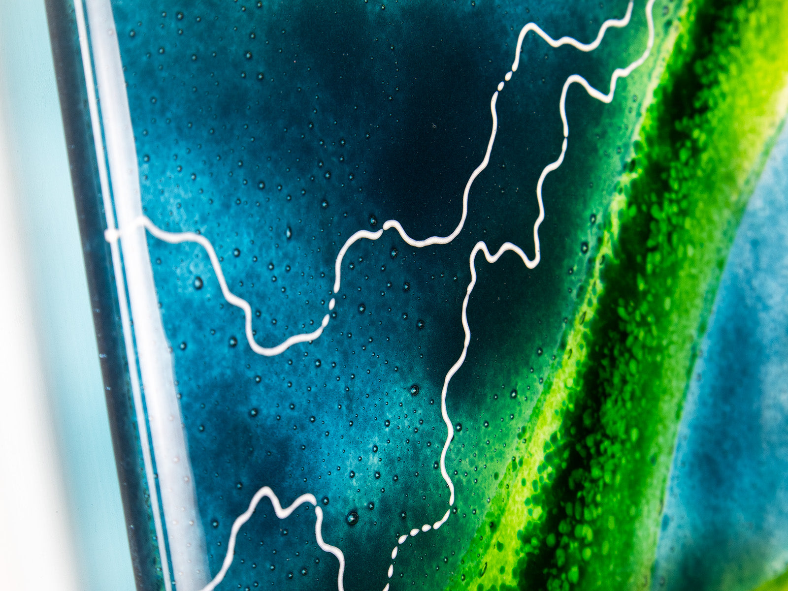A detailed image of a fused glass wall panel in vibrant marine colours, in an abstract design. Hand-made in our Cornish studio. 
