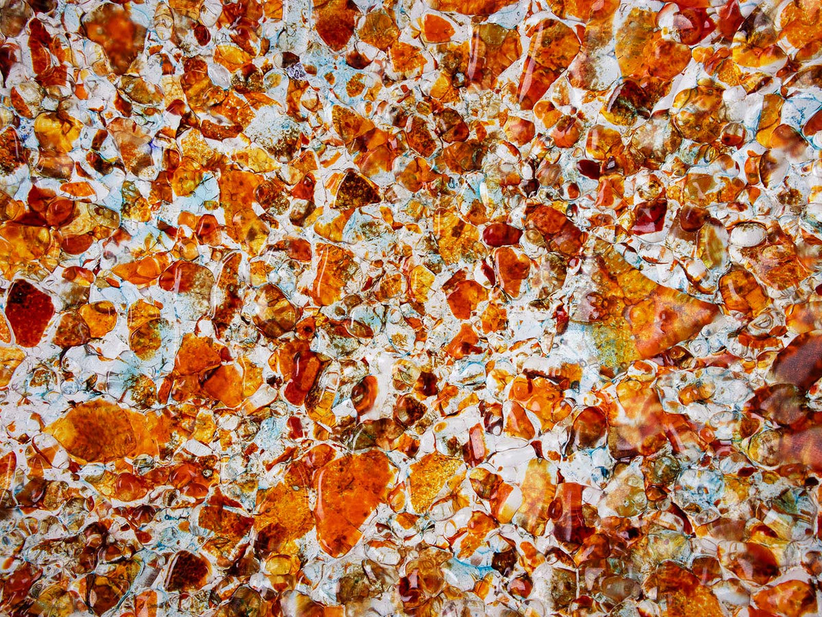 A close up of a fused glass round dish, handmade in vibrant recycled orange glass, creating a striking piece of art decor. 