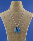 An artisan fused glass pendant necklace handcrafted in rich blues. Finished with a sterling silver chain and fittings, seen on a mannequin. 