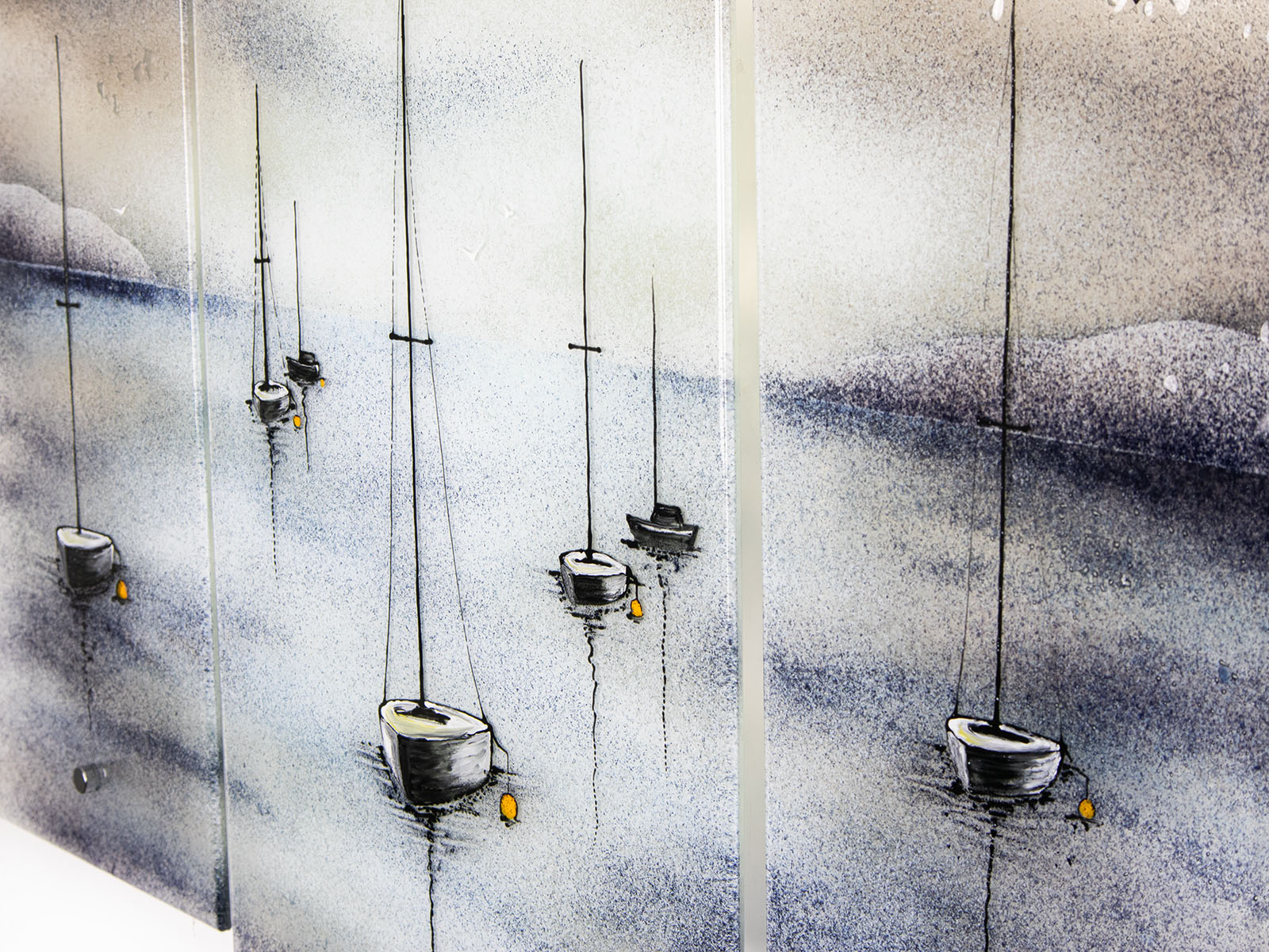 Details on a fused glass staggered triptych featuring a hand-painted sailboat design in a soft and misty colour-way. 