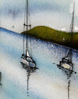 Details on a fused glass art frame featuring hand-painted sailing boats entering a harbour with soaring birds in a soft coastal colour-way. 