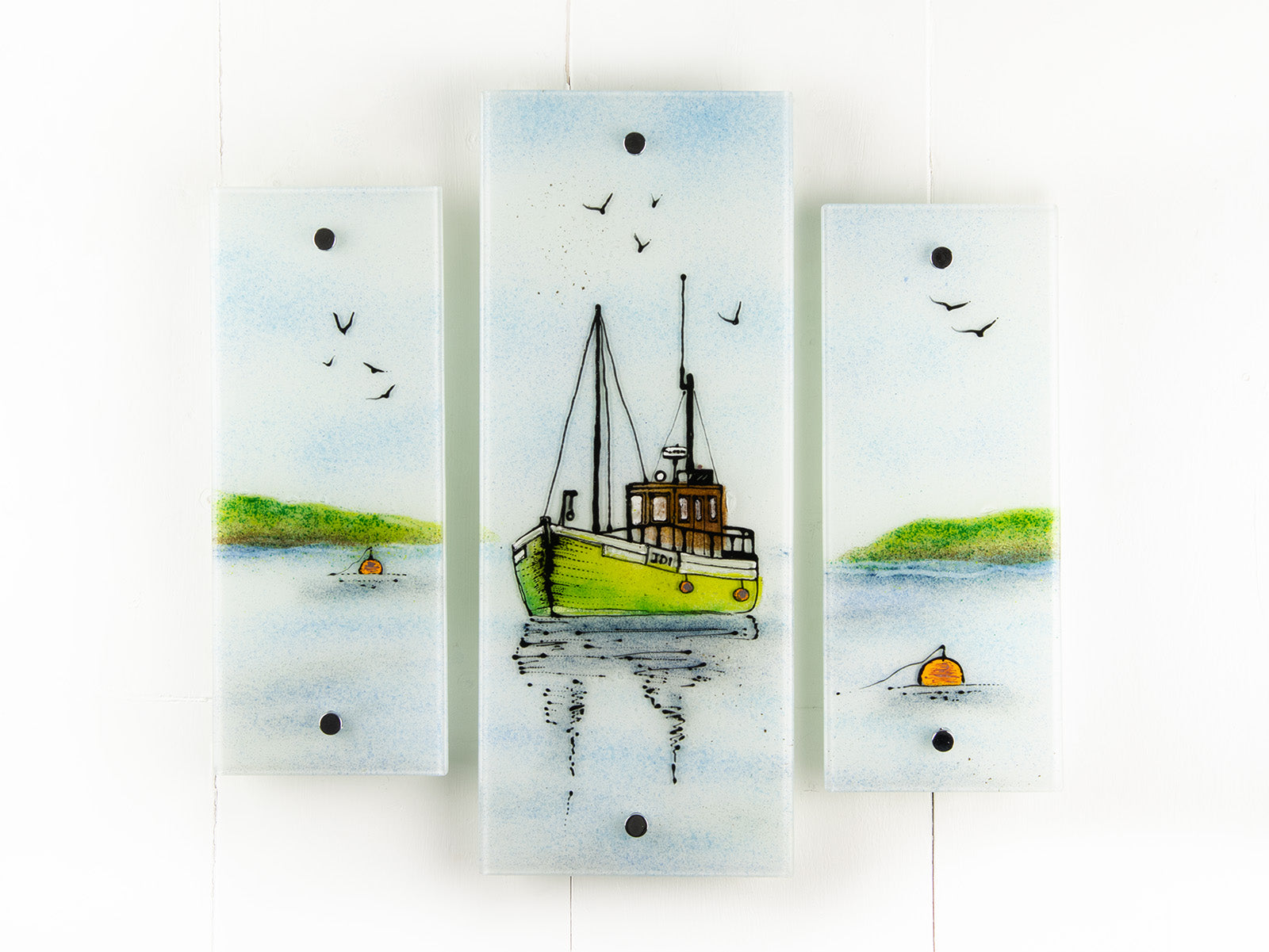 A staggered fused glass wall art triptych, with hand-painted fishing boat and a soft costal colour-way. 