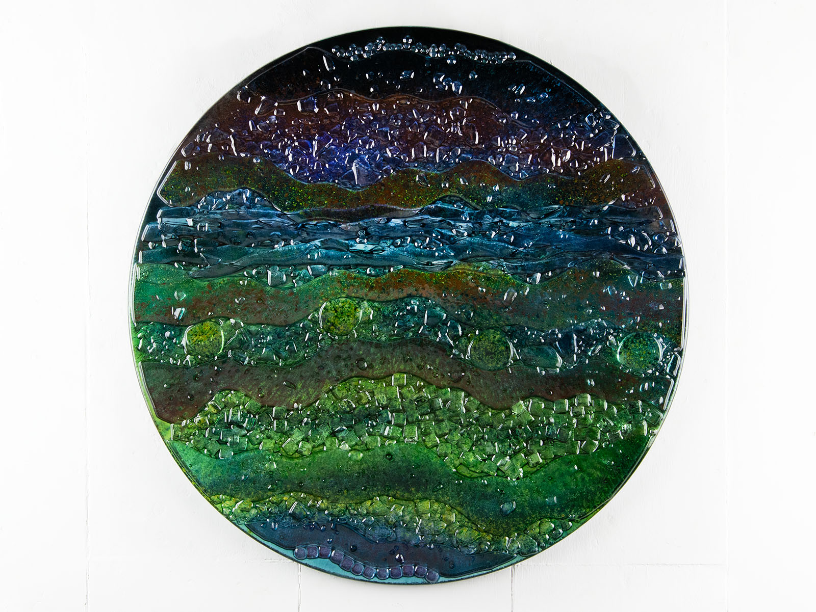 A round textured glass wall art piece featuring an abstract design with wavy organic hues.