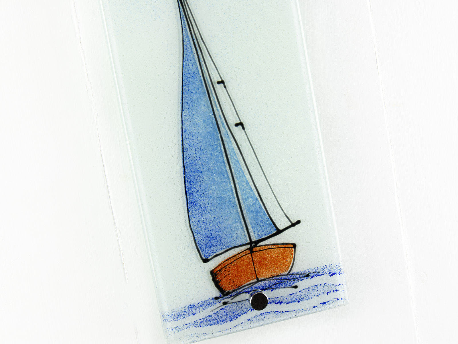 Close up of fused glass wall panel with a sail boat design, featuring coastal blue coloured sails.