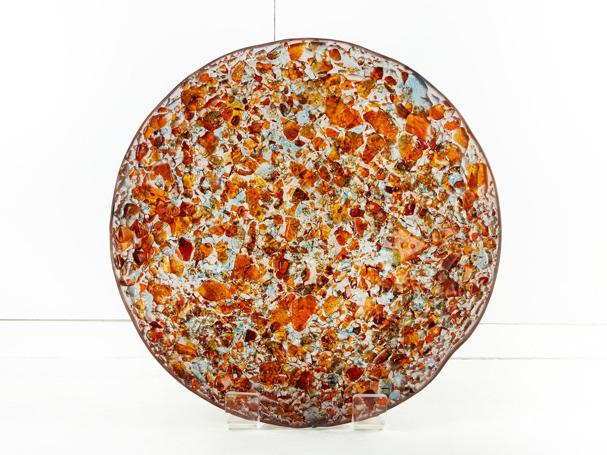 Fused glass round dish, handmade in vibrant recycled orange glass, creating a striking piece of art decor. 