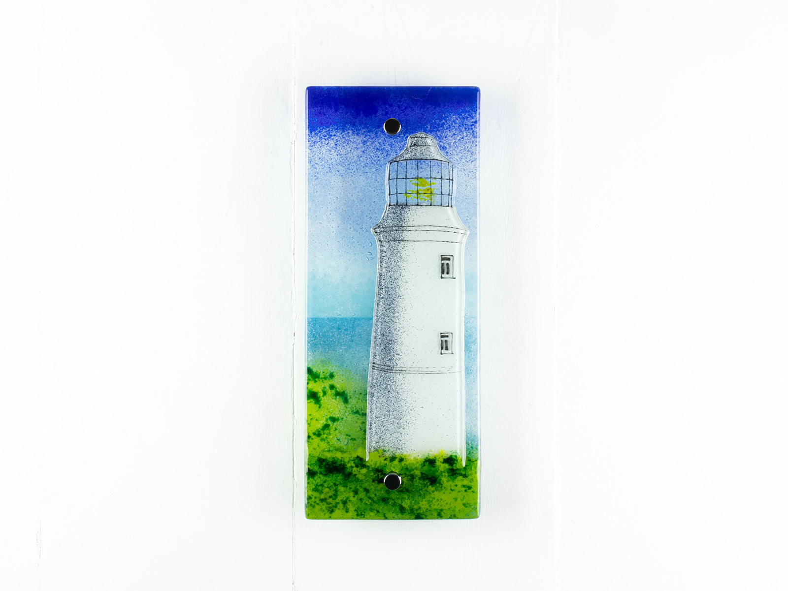 Fused glass wall panel with a lighthouse design, inspired by Cornish coast. Panel features bright coastal colours and organic detailing. 