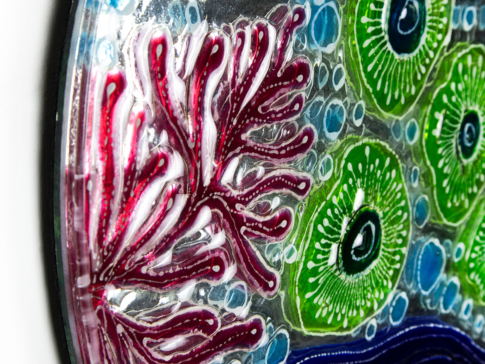 Detailing of fused glass round wall panel with hand painted design of a coral reef. Organic and vibrant ocean colours. 