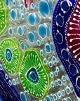 Close up of fused glass round wall panel with hand painted design of a coral reef. Organic and vibrant ocean colours. 