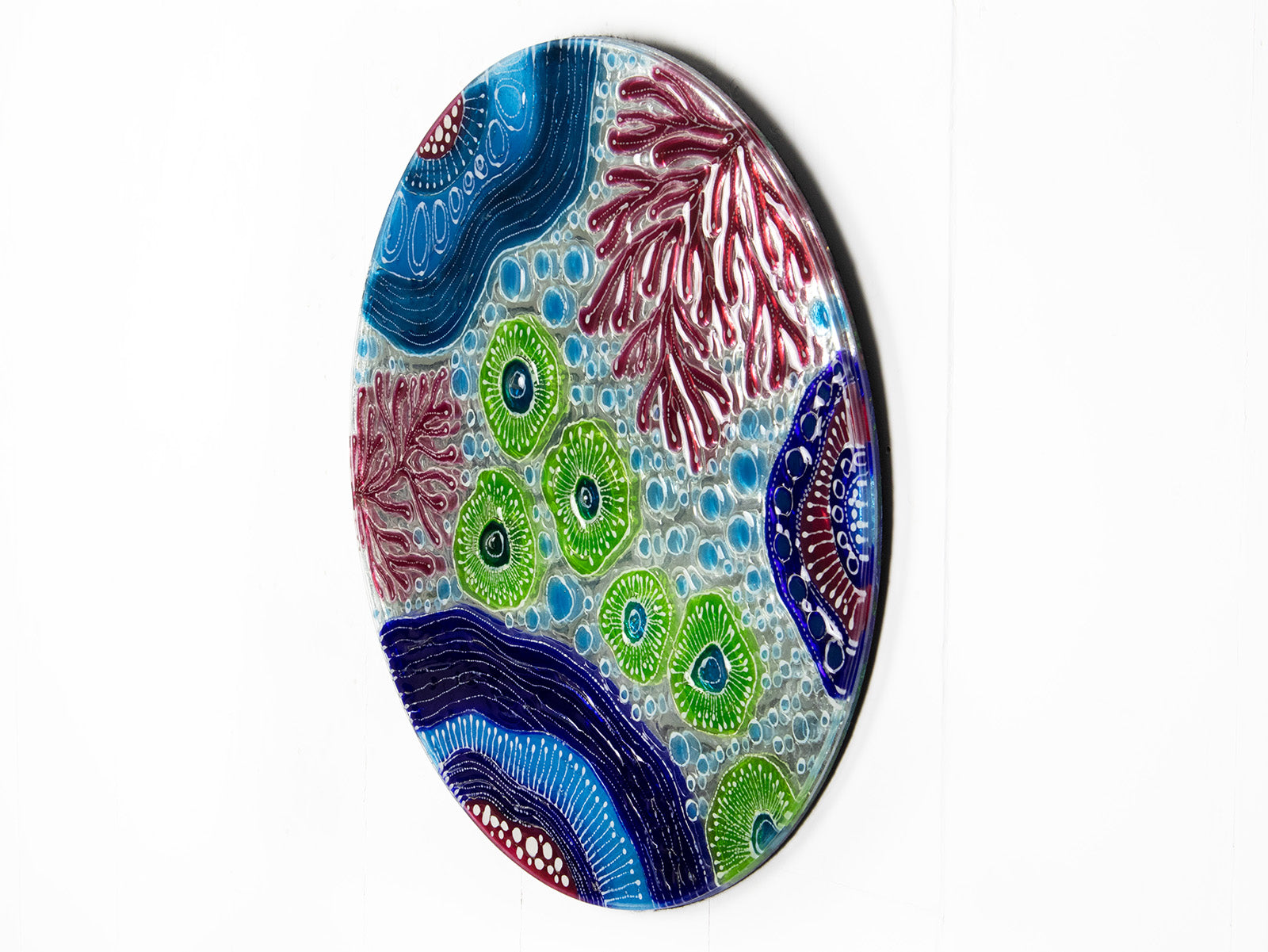 Fused glass round wall panel with hand painted design of a coral reef. Organic and vibrant ocean colours. 