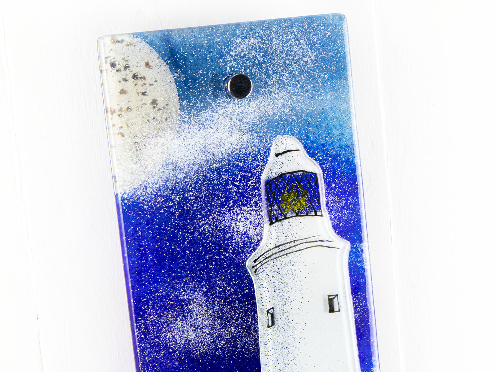 Close up of fused glass wall panel with lighthouse and moon design in coastal colours. Handmade glass panel, designed in Cornwall. 