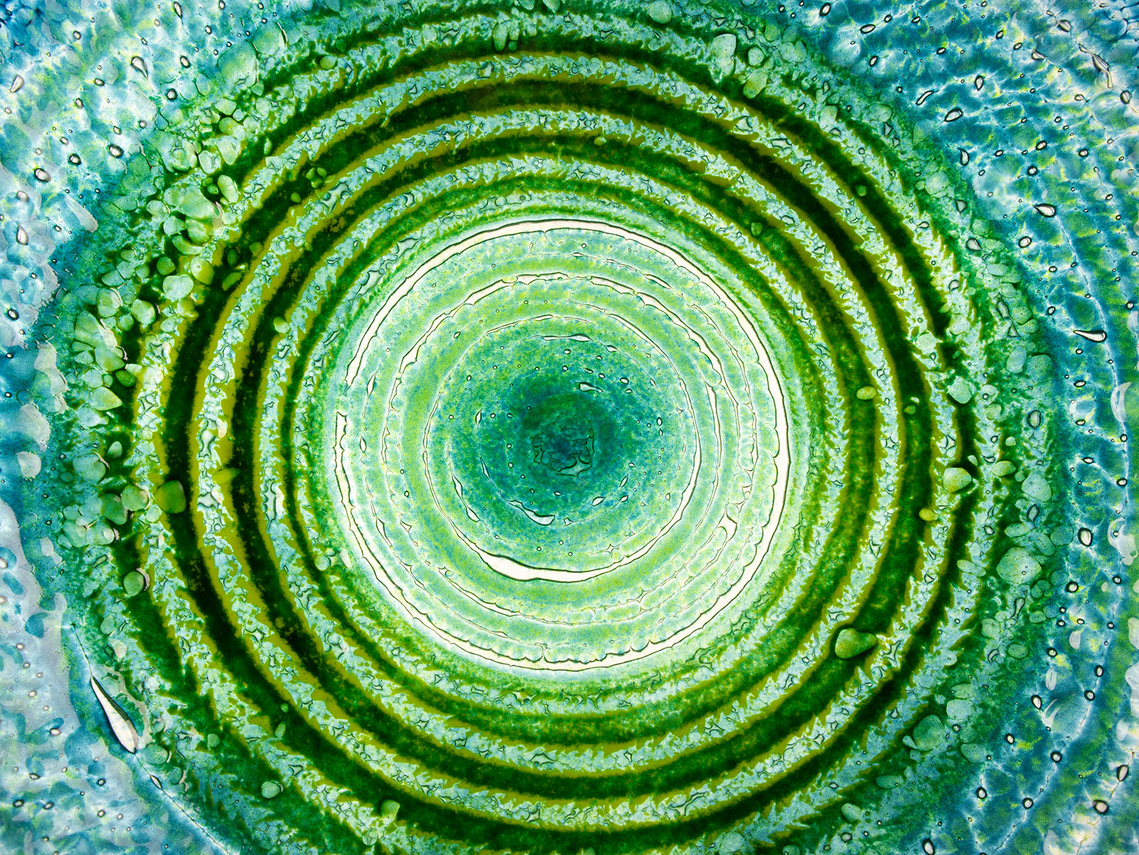 Close up shot of fused glass extra large dish made with ocean teals and greens with glass texture. Handmade in Cornwall, Launceston. 