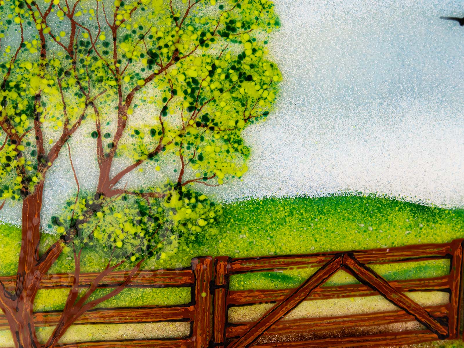 Close up of fused glass art frame with a countryside scene in vibrant colours, focused on a spring tree. 