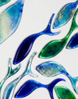 Close up of fish, individually hand-cut in marine blues on white art frame. An ocean inspired piece of wall art. 