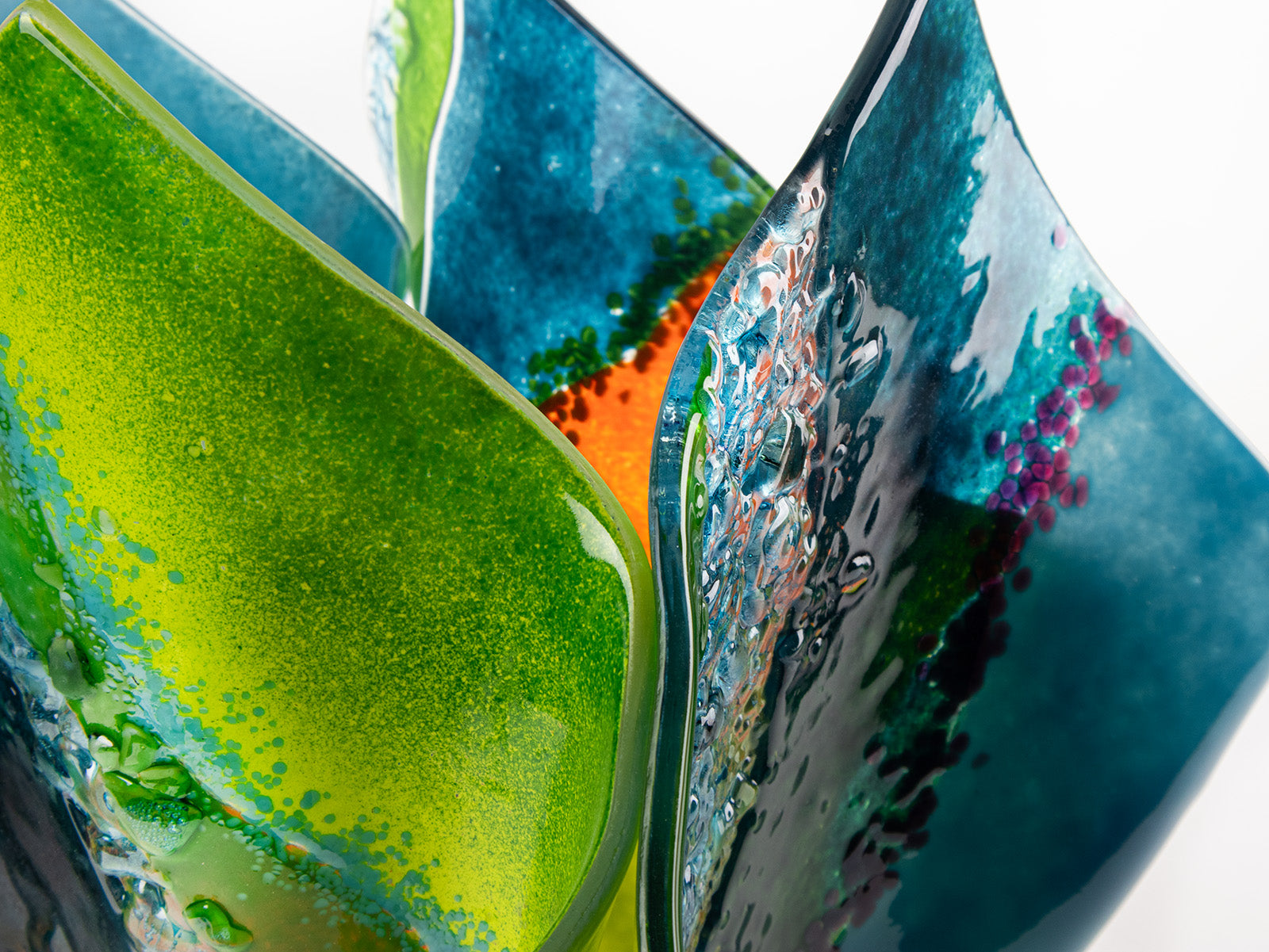 Details of fused glass fold form vase, with bright greens and textural detailing. 