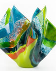 Main image of fused glass fold form vase, with bright greens and textural detailing. 