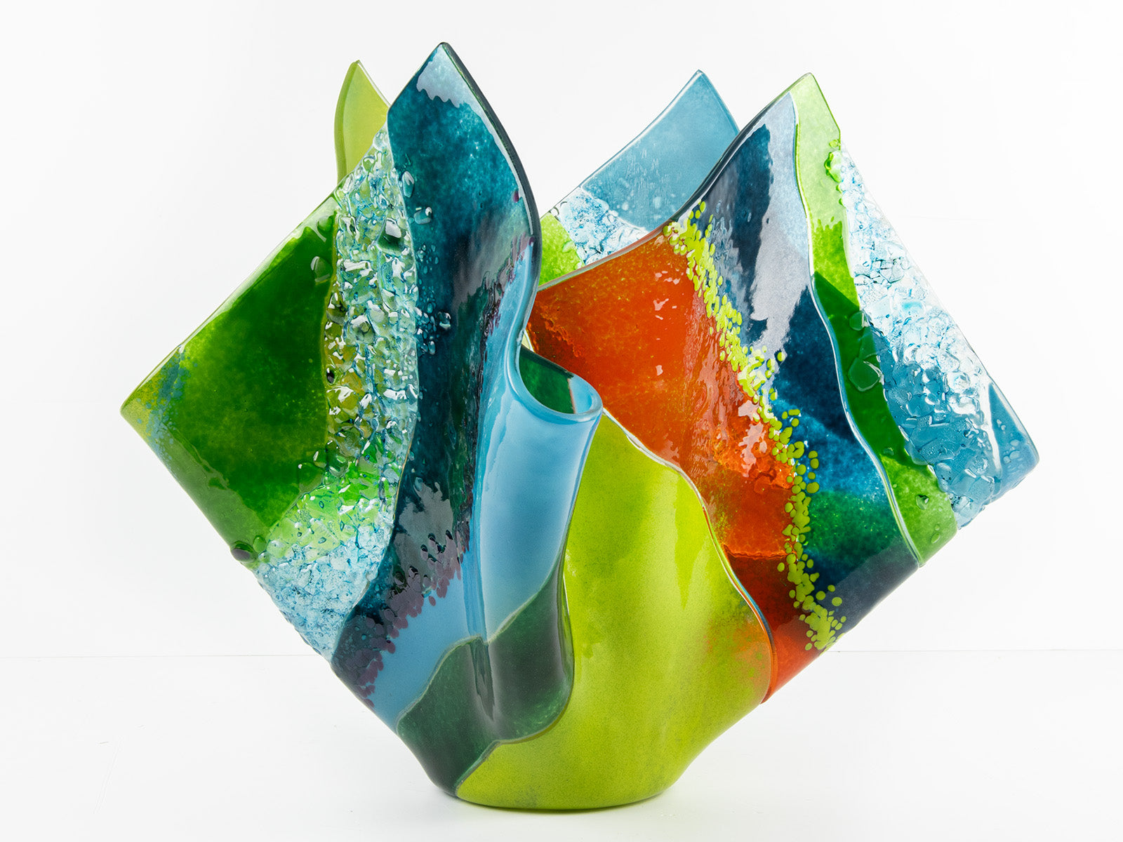 Second image of fused glass fold form vase, with bright greens and textural detailing. 