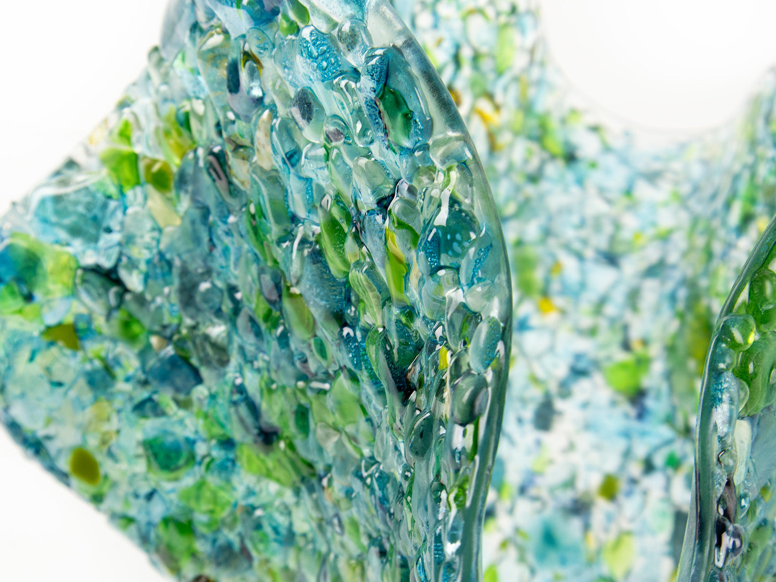 Close up of fused glass large vase, handmade from recycled glass in ocean green and blue hues. 