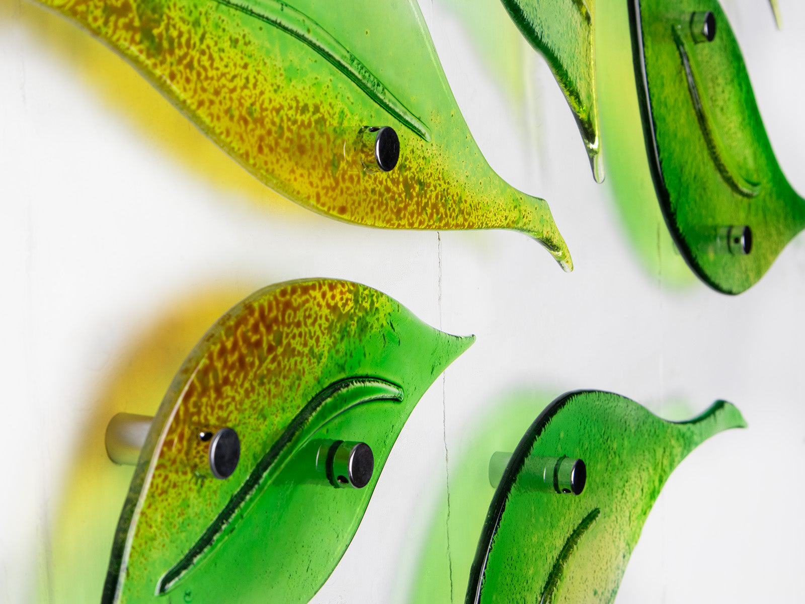 Details of fused glass wall art display featuring individual spring leaves in vibrant colours. 