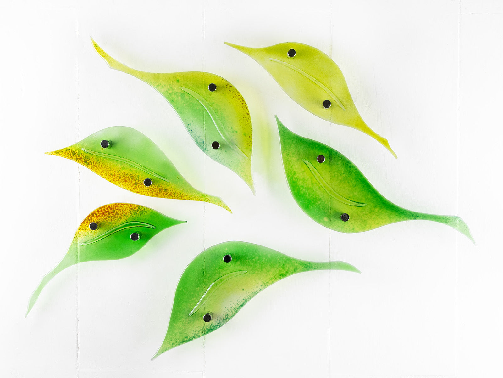 Fused glass wall art display featuring individual spring leaves in vibrant colours. 