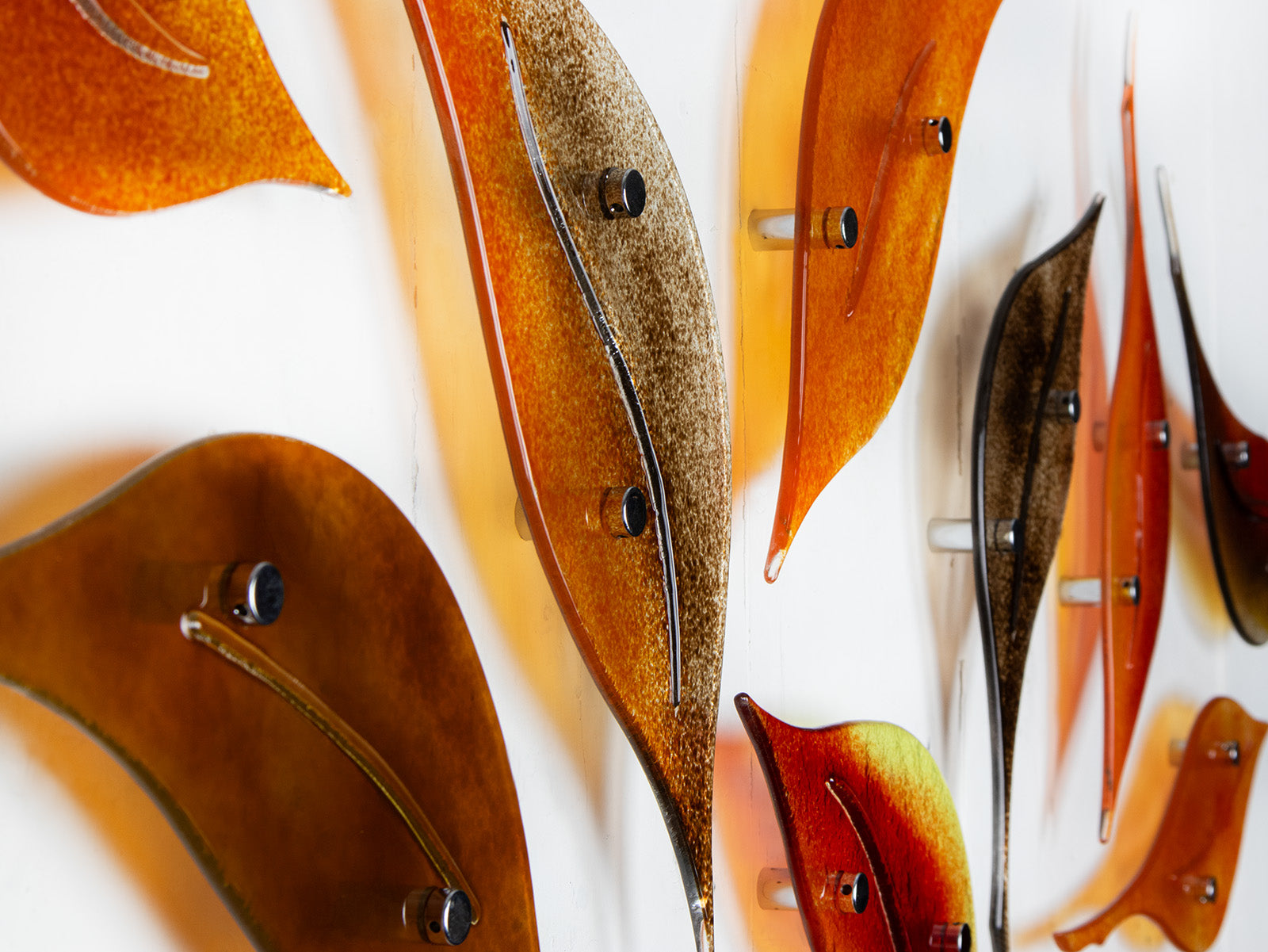 Close up of fused glass autumn leaf wall art display, in vibrant orange and natural browns. 