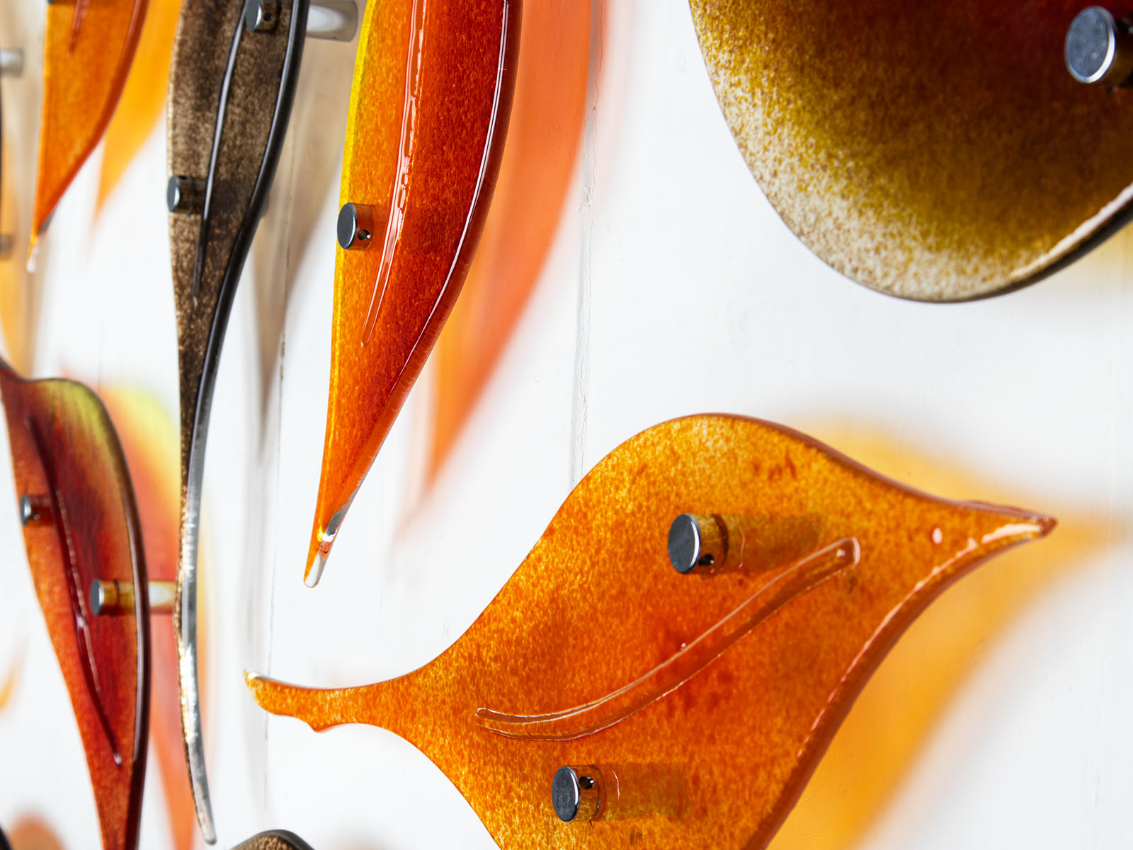 Details of fused glass autumn leaf wall art display, in  vibrant orange and natural browns. 