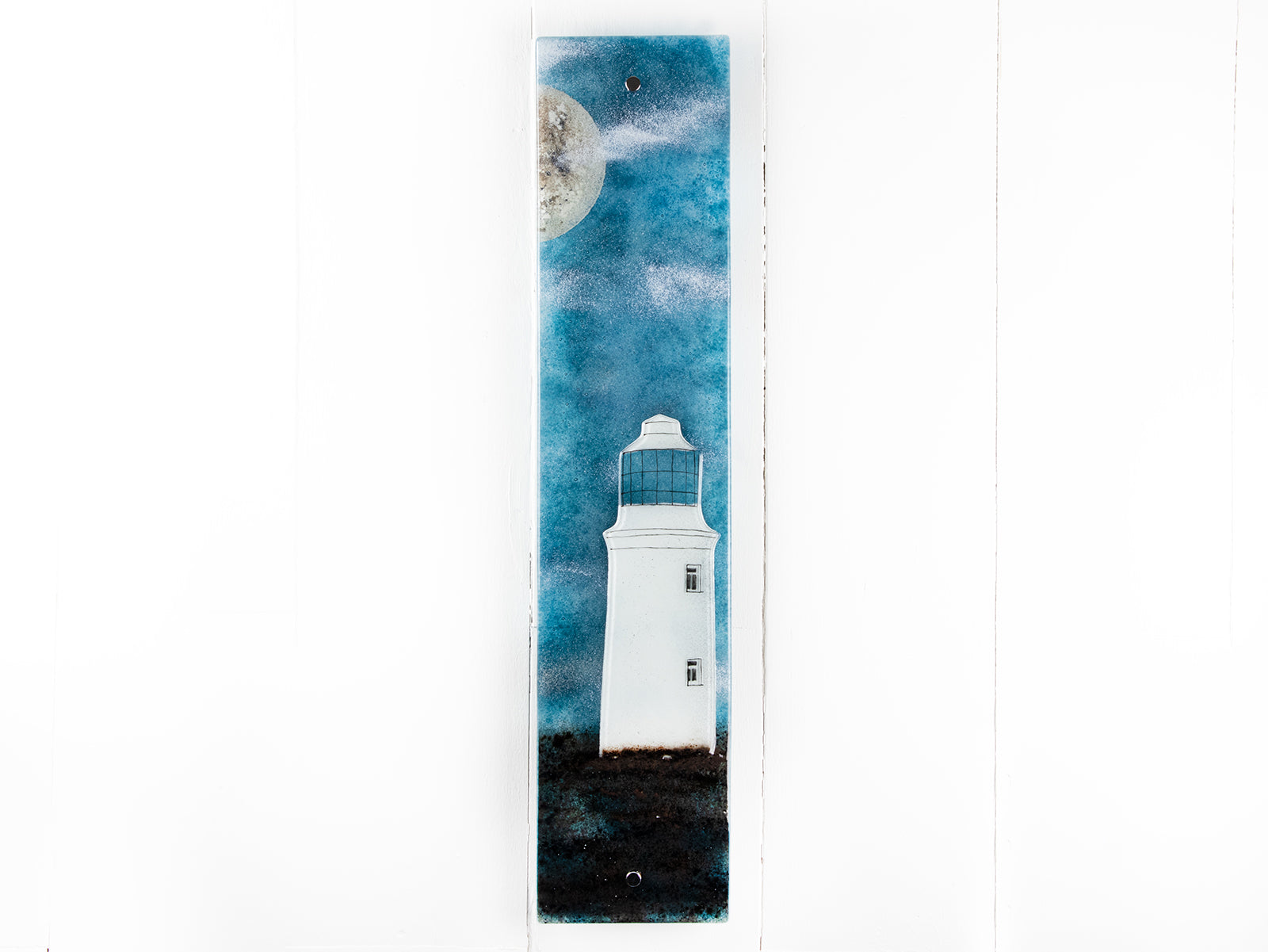Fused glass wall panel featuring a Cornish lighthouse design with a teal blue background and full moon design. 