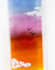 Close up of a fused glass wall panel, featuring a Cornish lighthouse design with a sunset sky and soaring gulls. 