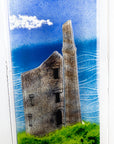 Close up of a fused glass wall panel featuring a Cornish lighthouse sat against a coastal blue design.  