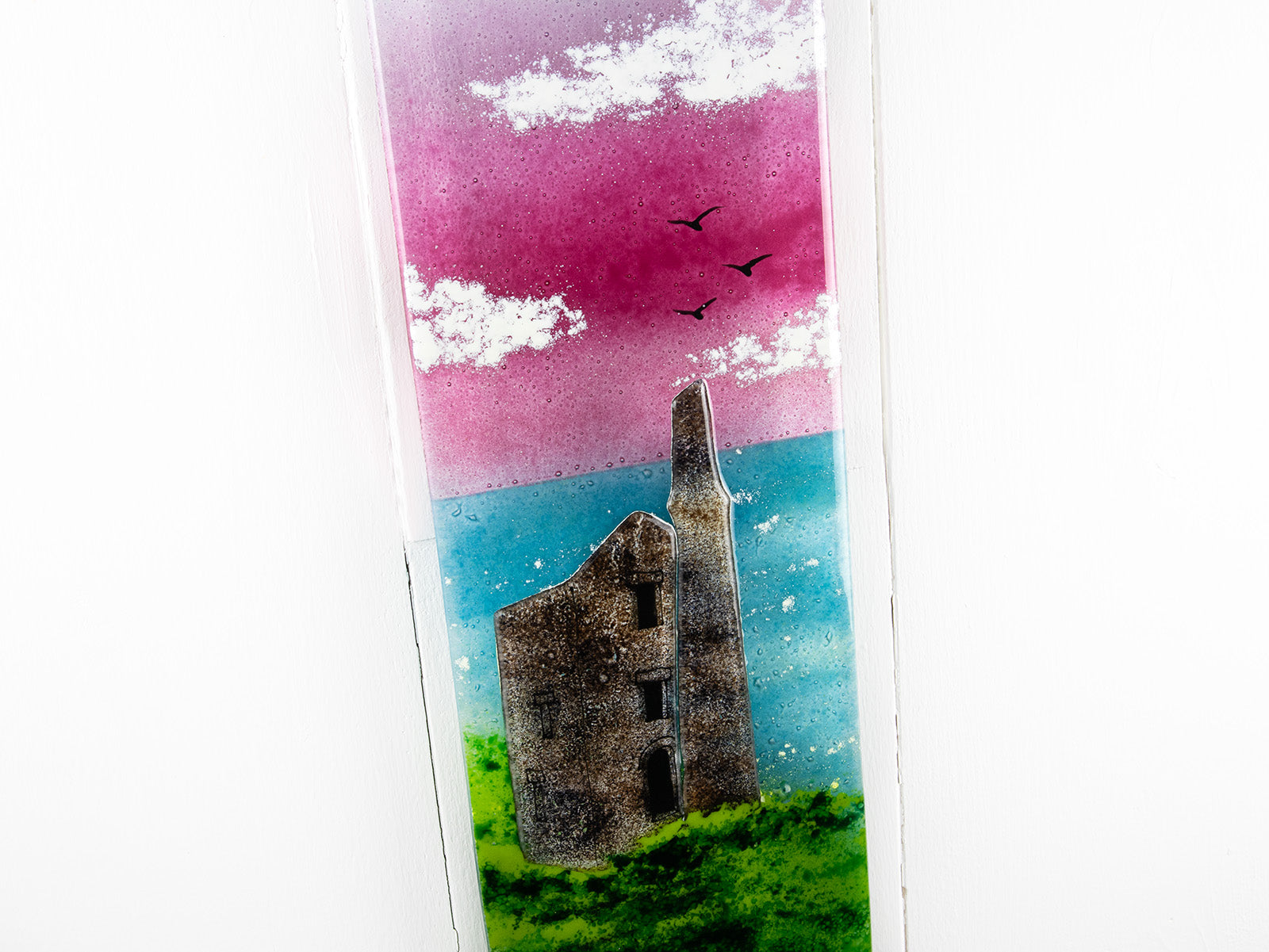 Close up of fused glass wall panel featuring a Cornish tin mine, with a vibrant sunset sky and soaring gulls. 