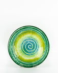 Fused glass round dish featuring bright sea greens and swirling aqua detailing. 
