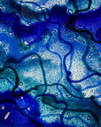 Close up of a fused glass round dish, featuring ocean blue colours and organic detail. 