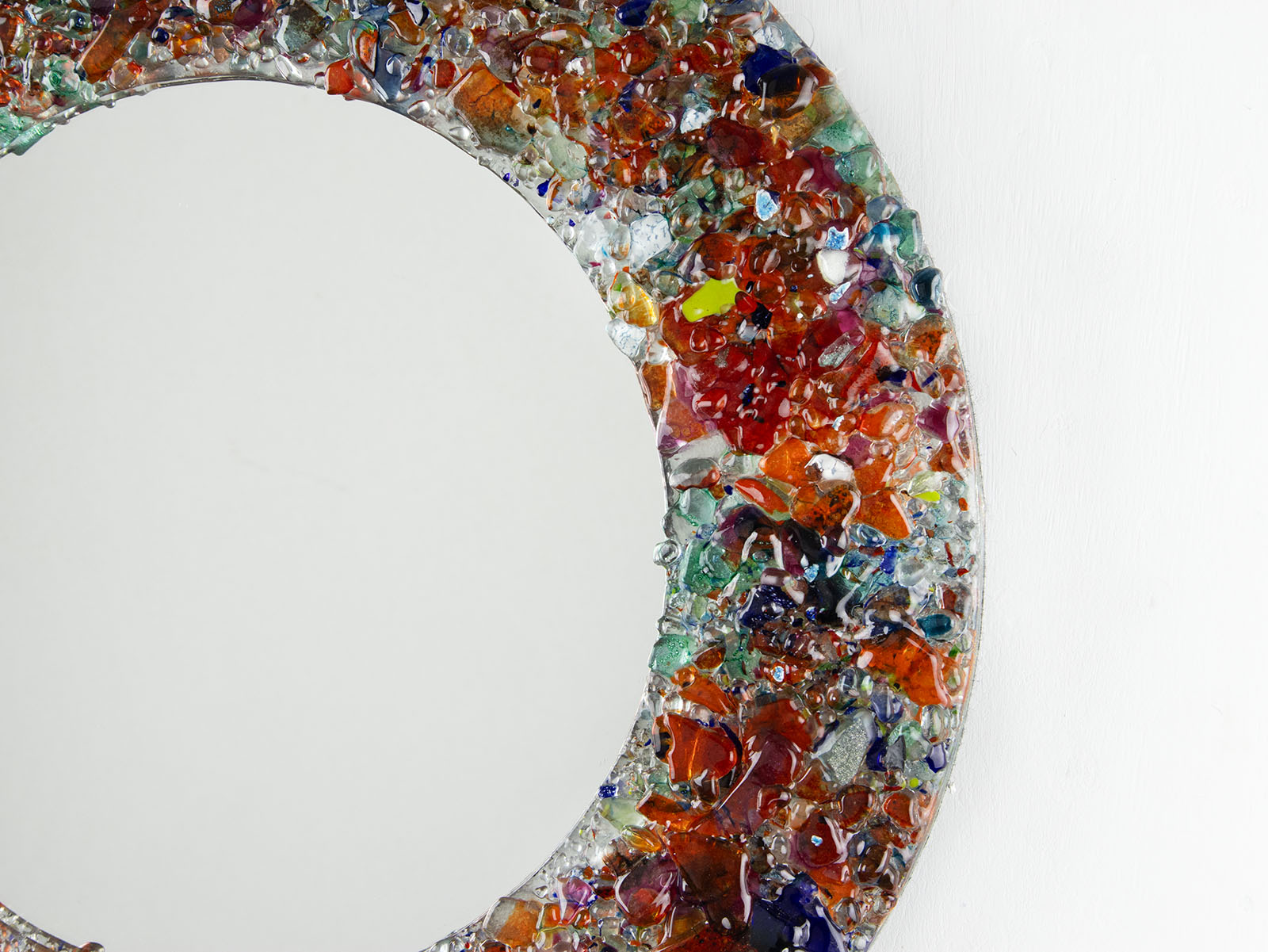 Details of fused glass round mirror, made from recycled glass in sunset orange and reds