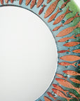 Details of fused glass round mirror featuring a soft, coastal colour-way with copper fish, creating an ocean inspired piece of wall art.