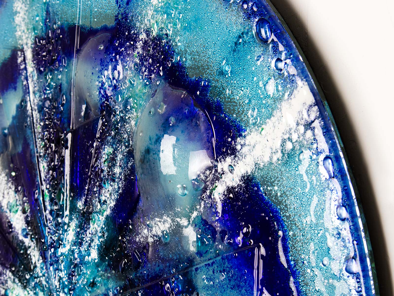 Close up of a big bubble on fused glass round panel with sea blues and textural detail. 