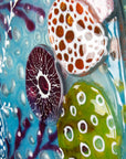 Details of hand-painted anemone in bright pinks on a fused glass round wall panel.  