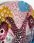 Close up of fused glass round wall panel with starfish and ocean reef design in pinks and sea blues. 