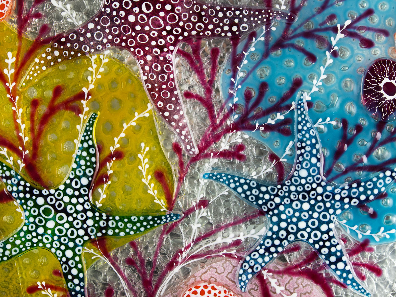 Close up of starfish design in bright pinks and sea blues, inspired by he ocean reefs on a fused glass piece of wall art.
