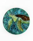 Fused glass round panel with hand-painted sea turtle and aqua bubbled background. An ocean inspired piece of wall art. 